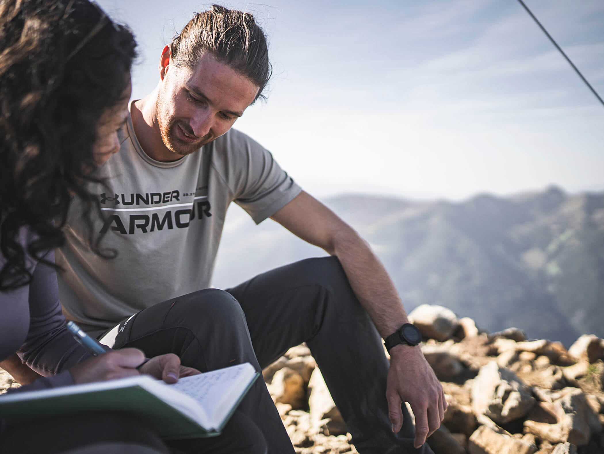 A couple writes in the book of the summit cross - Berghotel Alpenfrieden