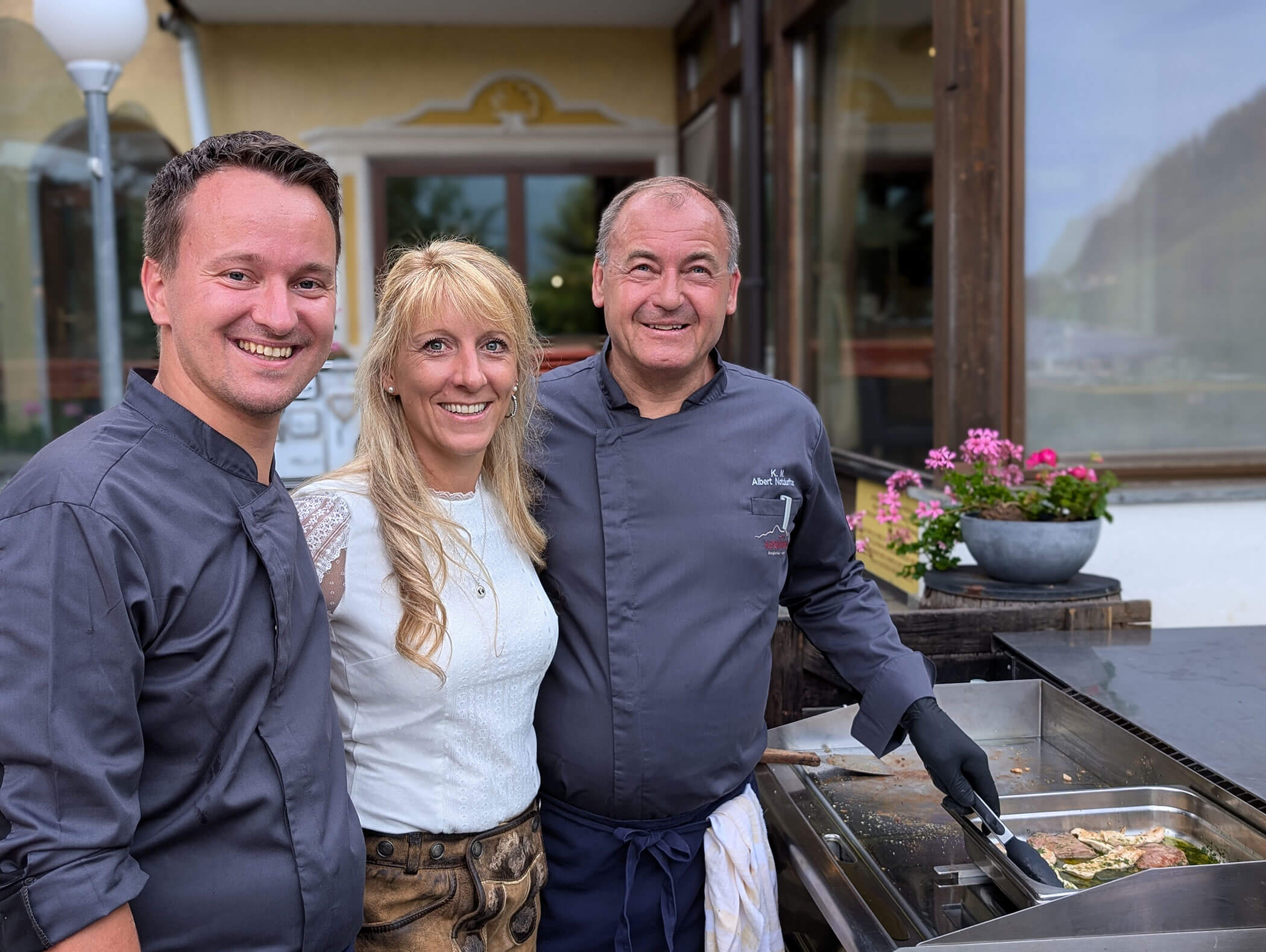 Two chefs and the hostess smile at the camera