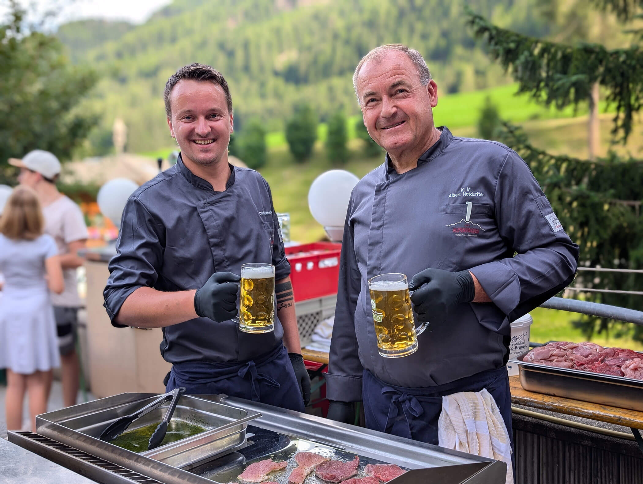 Two chefs at the barbecue with a beer in their hands