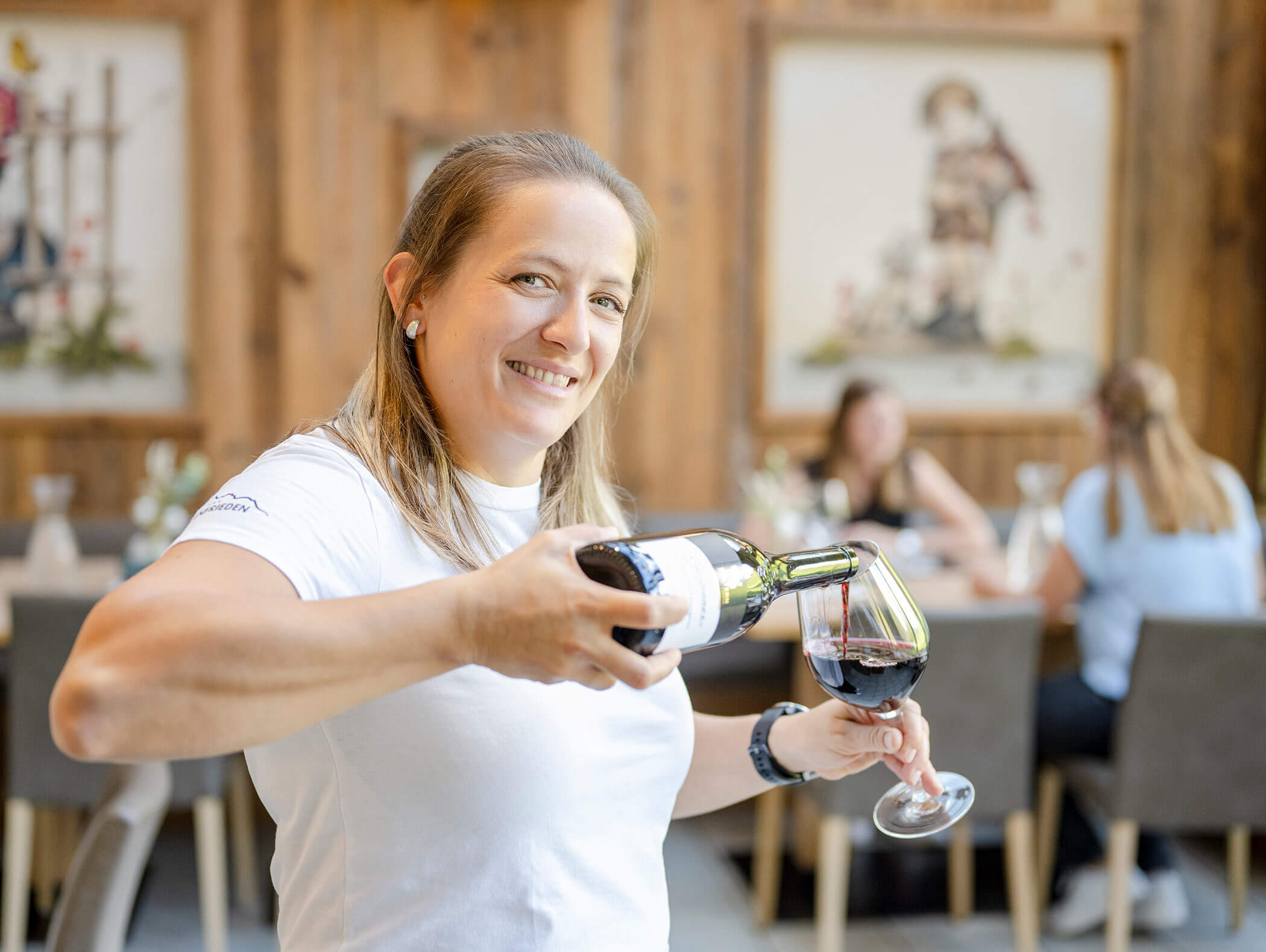 Cameriera versa vino rosso nel bicchiere - Berghotel Alpenfrieden