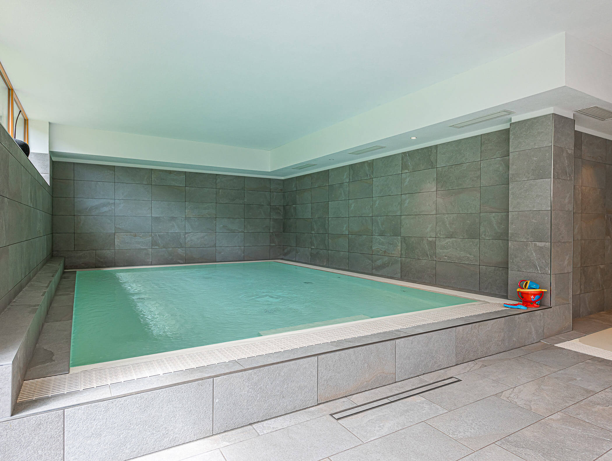 Swimming pool with children's toys at the edge - Berghotel Alpenfrieden