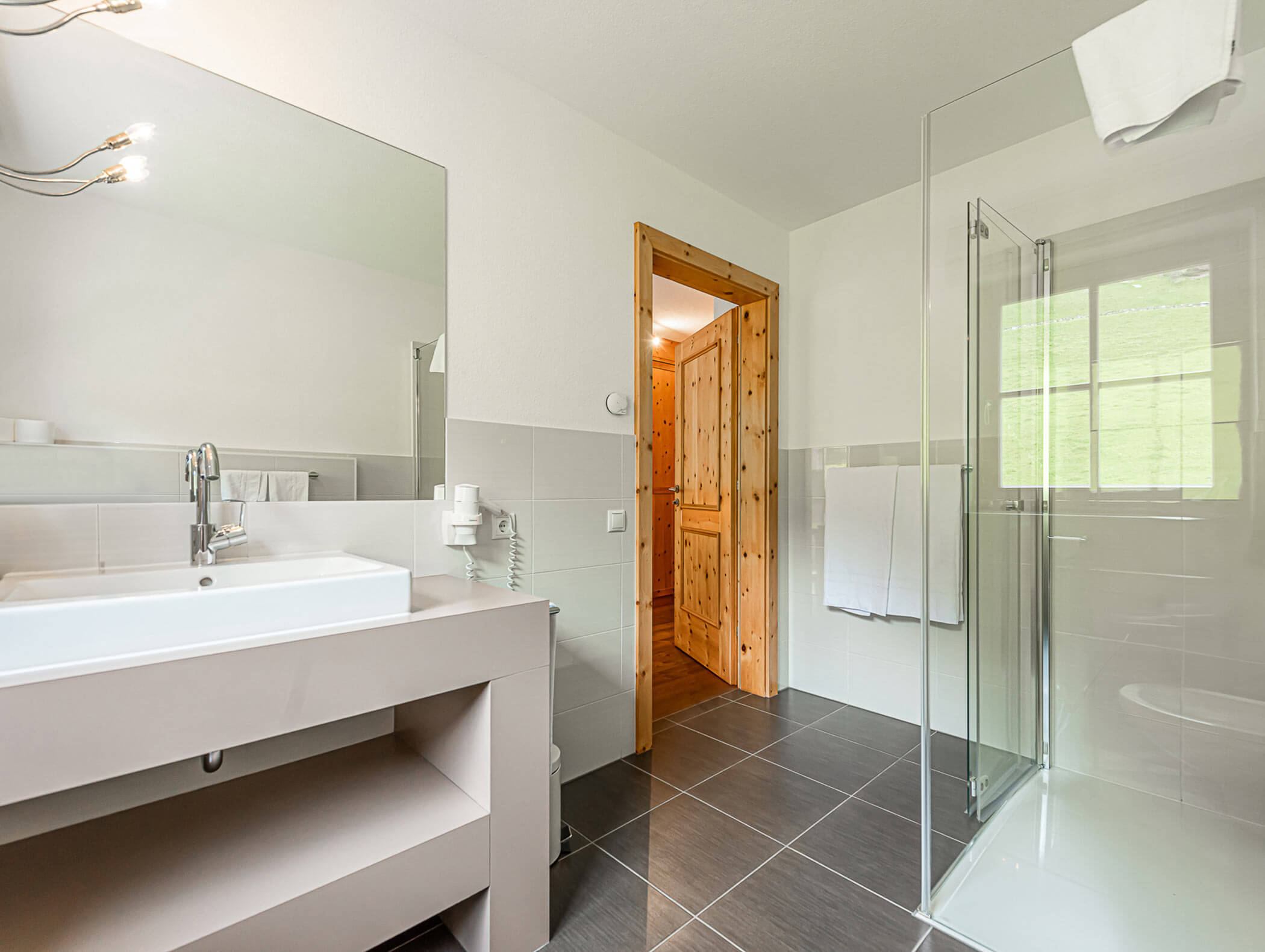 Badezimmer vom Dependance Deluxe Zimmer mit Waschbecken, Spiegel und Dusche - Berghotel Alpenfrieden