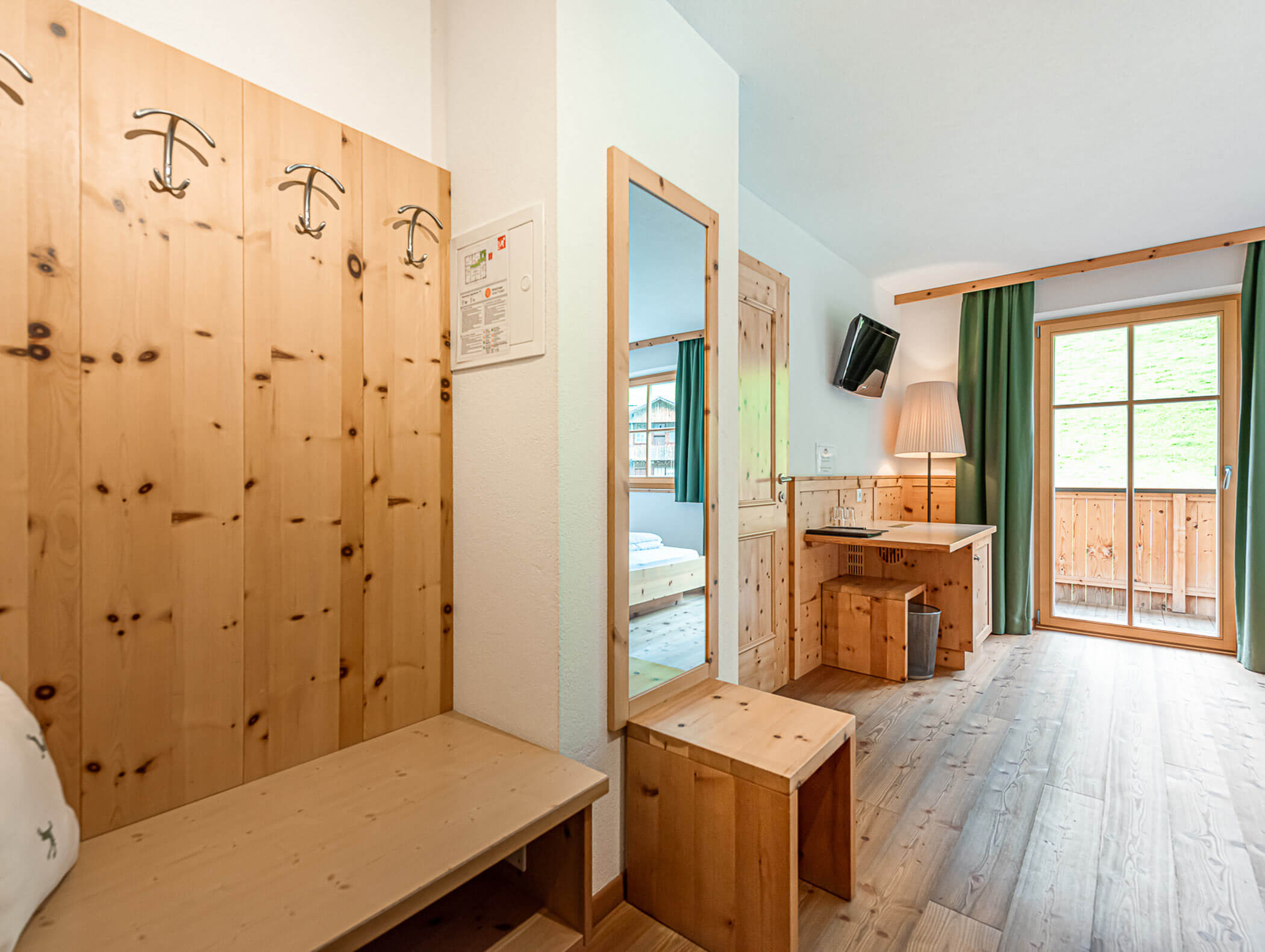 Eingangsbereich des Dependance Deluxe Zimmers mit Blick auf TV und Balkon - Berghotel Alpenfrieden