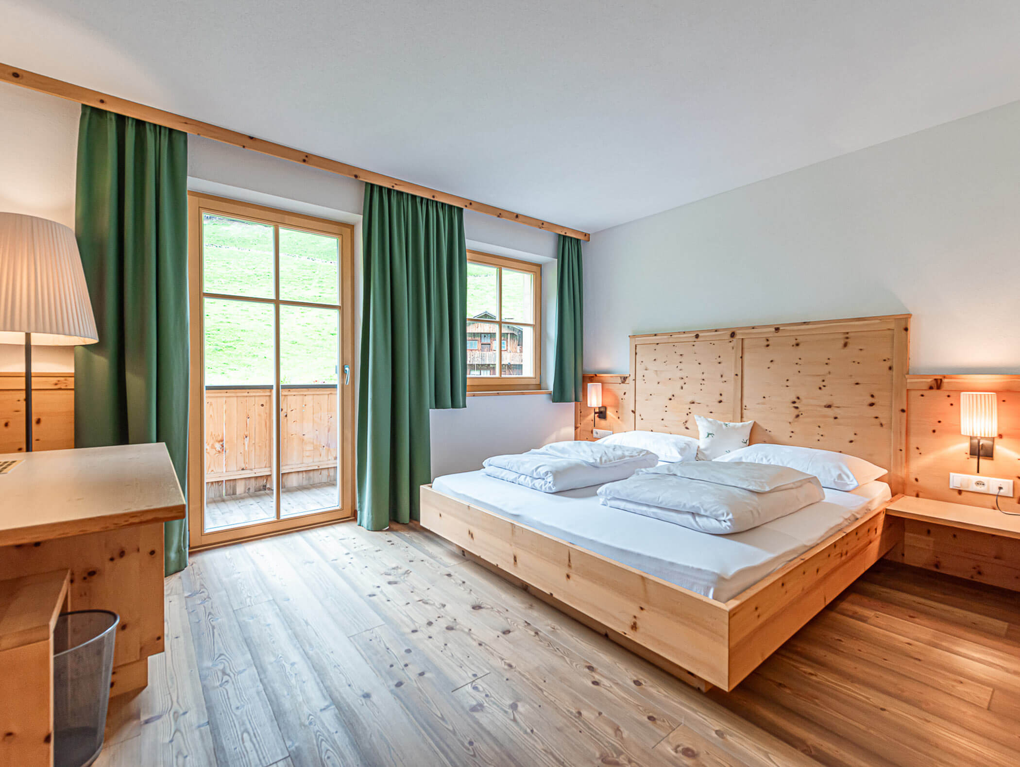 Dependance Family Suite mit Doppelbett und grünen Vorhängen - Berghotel Alpenfrieden