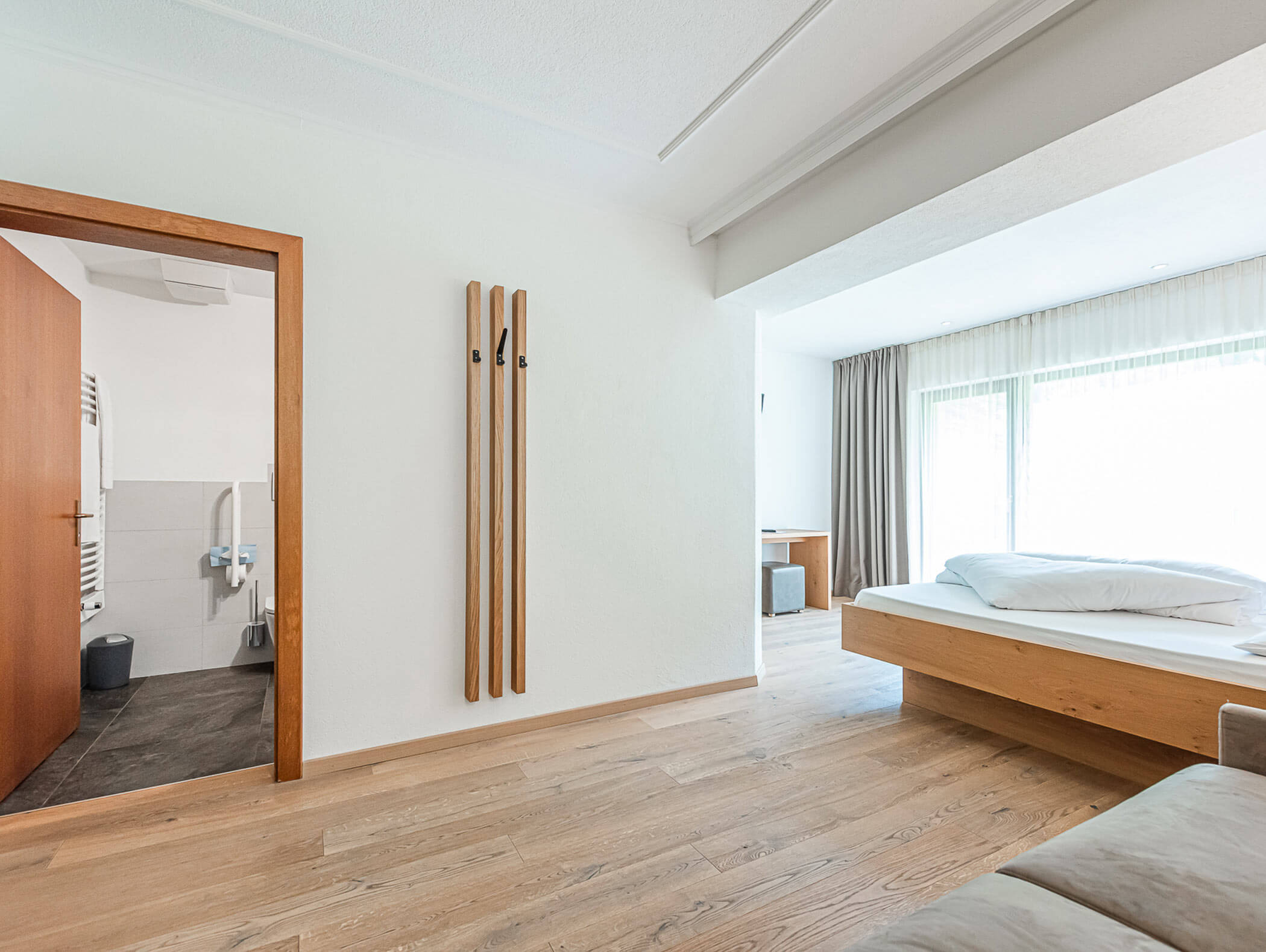 Berghotel Superior Zimmer mit Blick vom Sofa auf Doppelbett und Bad - Berghotel Alpenfrieden